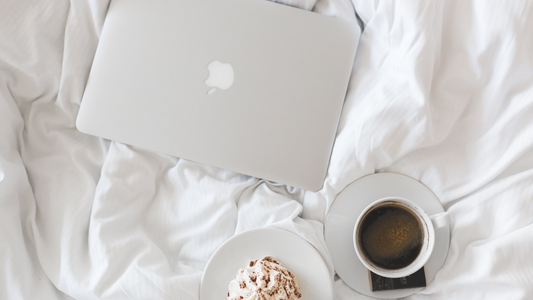 Apple MacBook on comfy bed with coffee