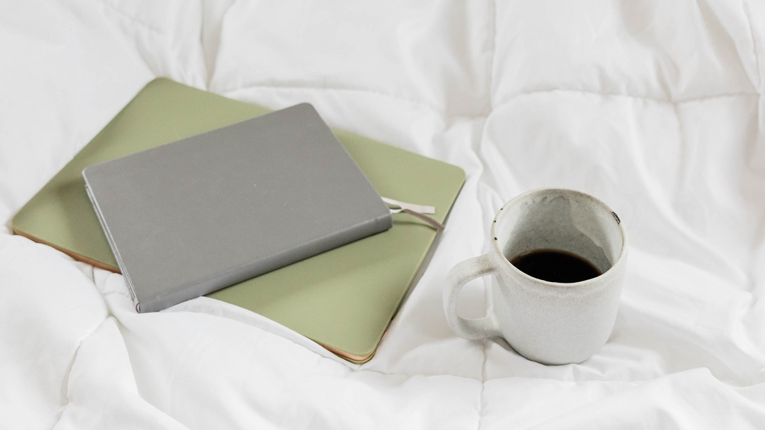 Notebook on iPad with coffee sitting on bed. 